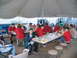 1995 Ford C-350 (Centurion Conversions) - People gather for a meal under a large tent, with a forklift visible in the distance.
