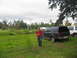 1995 Ford C-350 (Centurion Conversions) - A man walks past two SUVs parked in a grassy area under an overcast sky.