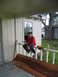 1995 Ford C-350 (Centurion Conversions) - A young boy sits on a white porch railing, with a large piece of wood in the foreground and a tree in the background.