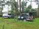 1995 Ford C-350 (Centurion Conversions) - Two vehicles, a Ford F-Series truck and an SUV, are parked in a grassy area with trees in the background.