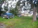 1995 Ford C-350 (Centurion Conversions) - A dark blue SUV with chrome trim is parked in a grassy yard next to a small house.