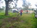 1995 Ford C-350 (Centurion Conversions) - Two individuals are clearing debris from a yard after a storm, with vehicles parked nearby.