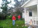 1995 Ford C-350 (Centurion Conversions) - Two men assess damage and clear debris from a yard after a fallen tree impacted a house.