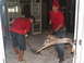 1995 Ford C-350 (Centurion Conversions) - Men in red SEMA shirts clear debris from a room, likely after damage or renovation.