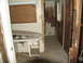 1995 Ford C-350 (Centurion Conversions) - The interior of a room shows significant damage to the walls and flooring, with a sink and ironing board visible.