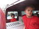 1995 Ford C-350 (Centurion Conversions) - Two boys are inside the cab of a red truck, with one boy looking out the window and the other looking towards the camera.