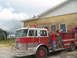 1995 Ford C-350 (Centurion Conversions) - A group of children are gathered around a fire truck outside a yellow brick building.