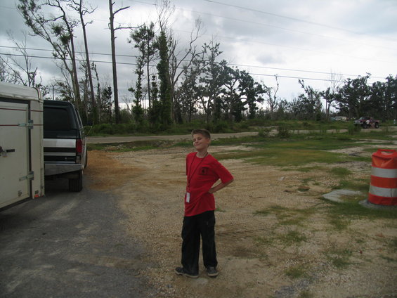 Silver truck and trailer parked next to a boy in a red shirt