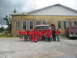 1995 Ford C-350 (Centurion Conversions) - A group of people, some in red shirts, stand in front of a fire truck and a brick building.
