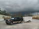 1995 Ford C-350 (Centurion Conversions) - A Ford Bronco tows a trailer in front of modular buildings under a dark, stormy sky.