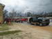 1995 Ford C-350 (Centurion Conversions) - A dark green Ford Bronco is parked with a trailer, while a fire truck and people in red shirts are visible in the background.