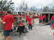 1995 Ford C-350 (Centurion Conversions) - People in red shirts unload items from a trailer near a fire truck.