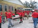 1995 Ford C-350 (Centurion Conversions) - Volunteers in red shirts are seen moving furniture outside a building, with a fire truck in the background.