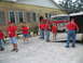 1995 Ford C-350 (Centurion Conversions) - A red fire truck is parked in front of a brick building, with several people in red shirts standing nearby.