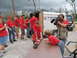 1995 Ford C-350 (Centurion Conversions) - A group of people, some wearing red shirts with 'SEMA' on them, are gathered near a trailer and a pickup truck. A cameraman is filming the…