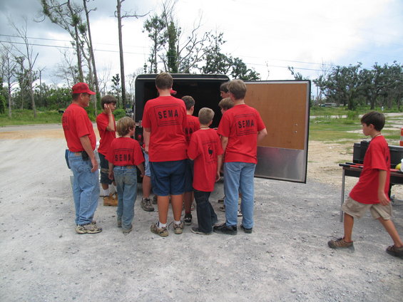 Group of people in red SEMA shirts unloading a trailer