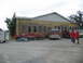 1995 Ford C-350 (Centurion Conversions) - A fire truck is parked in front of a yellow brick building with people gathered around tables.