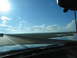 1995 Ford C-350 (Centurion Conversions) - A lone vehicle travels across a bridge, with marshland and water visible to the side under a vast, blue sky.