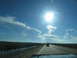 1995 Ford C-350 (Centurion Conversions) - Driving on a highway with a bright sun and scattered clouds overhead. Another vehicle is visible in the distance.
