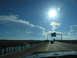 1995 Ford C-350 (Centurion Conversions) - View from a vehicle driving on a highway bridge under a bright sun and blue sky with clouds.