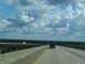1995 Ford C-350 (Centurion Conversions) - A dark SUV travels down a highway under a cloudy sky.