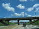 1995 Ford C-350 (Centurion Conversions) - Driving on a highway under a concrete overpass on a partly cloudy day.