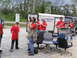 1995 Ford C-350 (Centurion Conversions) - People are gathered around a trailer and a dark van, some filming and others carrying chairs.