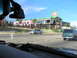 1995 Ford C-350 (Centurion Conversions) - Two vehicles drive past a damaged building with a large sign that reads 'Souvenir City'.