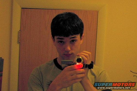 Young man holding a camcorder in front of a door