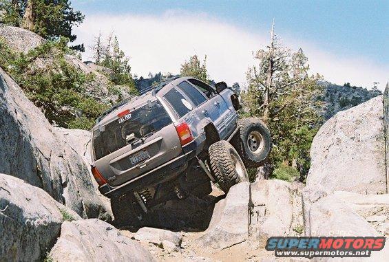 Gray Jeep Grand Cherokee with lifted suspension and large tires navigating a rocky trail