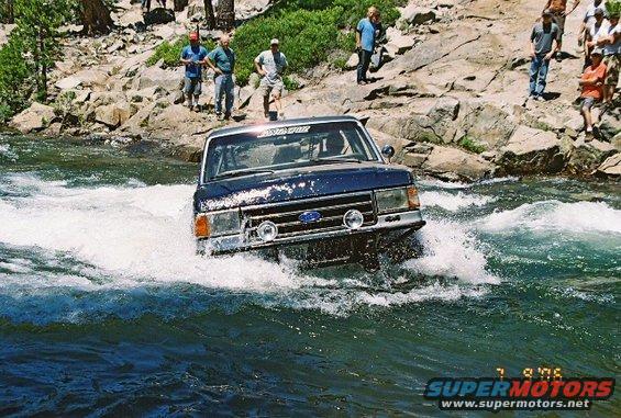 Ford Bronco driving through a river with people watching on the bank
