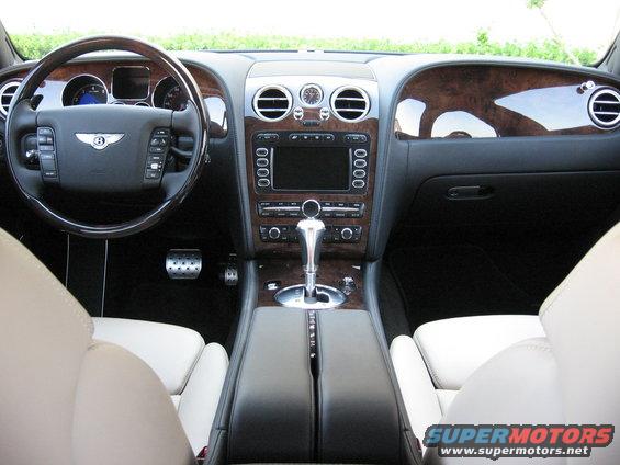 Interior view of a luxury car with wood trim and white leather seats