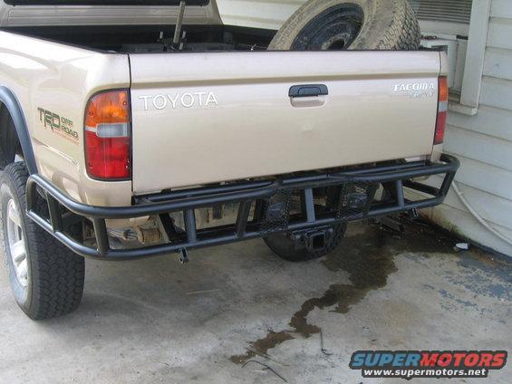 Rear view of tan Toyota Tacoma pickup with TRD Off Road decal and custom bumper