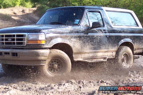 Muddy black Ford Bronco driving off-road, kicking up dirt