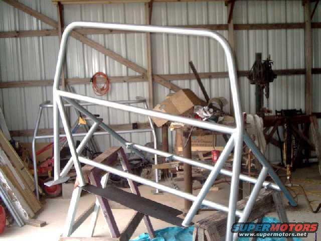 Silver roll cage assembly on sawhorses in a workshop