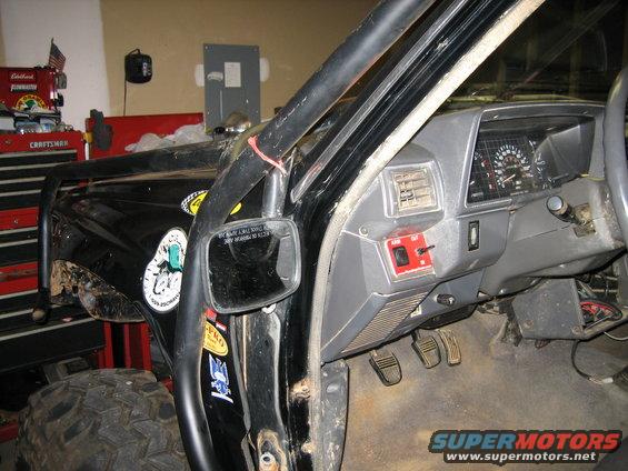 Interior view of a modified truck with a roll cage, aftermarket switches, and a dashboard with gauges