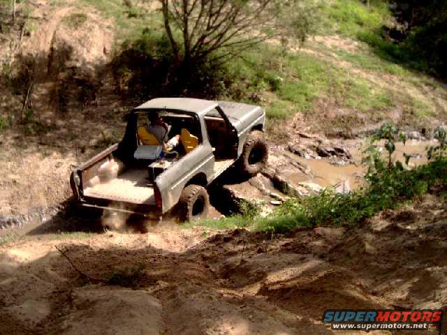 Gray off-road vehicle with yellow seats, driving through mud and dirt