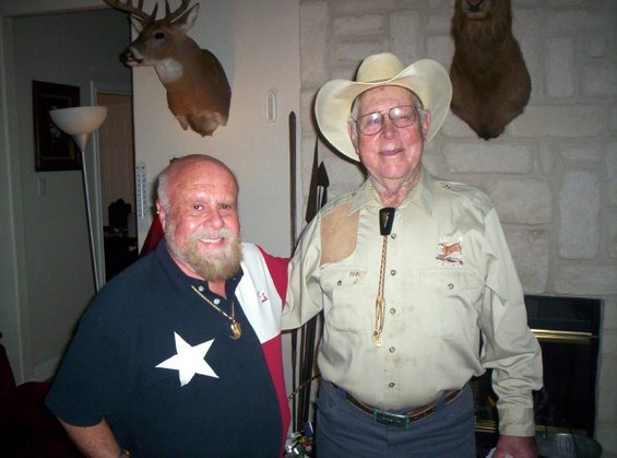 Two men posing indoors, one in a cowboy hat, the other in a star shirt