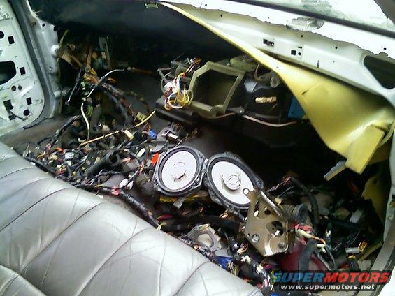 Car interior disassembled, showing speakers and a mess of wires under the dash