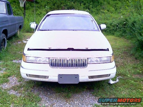 Front view of a white sedan with hood open and a chrome grille