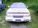2002 Ford Crown Victoria - A white sedan sits in a grassy area next to a dark-colored truck, with its hood propped open.