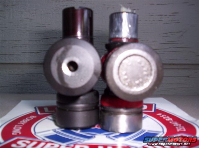 Two U-joints, one with a red boot, sit on a Supermotors logo