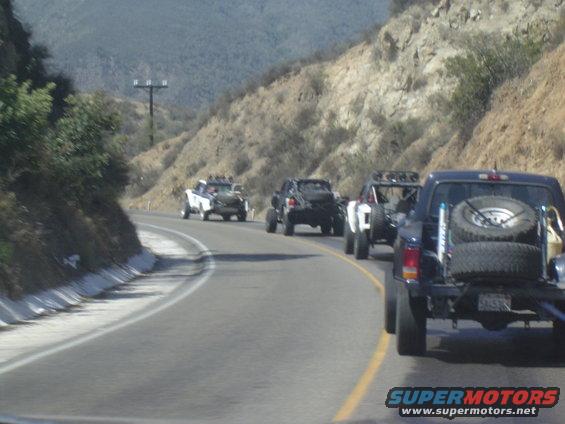 1985 Ford Ranger towing spare tires on a flatbed trailer, seen from behind