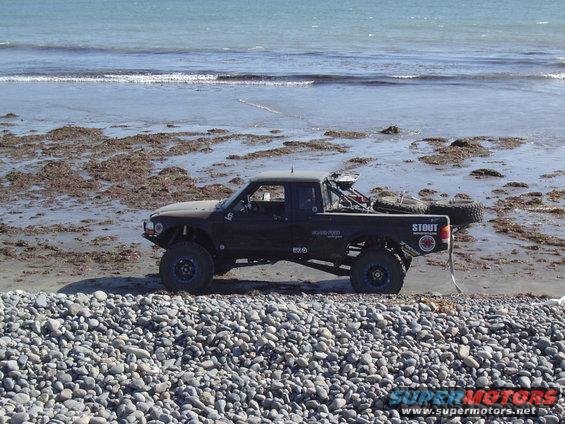 Black 1985 Ford Ranger Baja truck on beach, side view