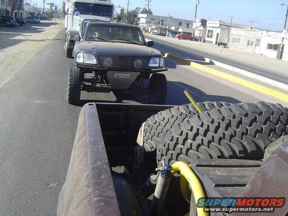 Pickup truck with off-road modifications towing a trailer on a road