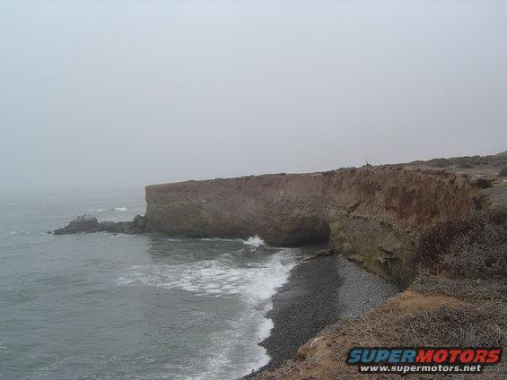 ocean waves crashing on a rocky shore with a cliff overhead
