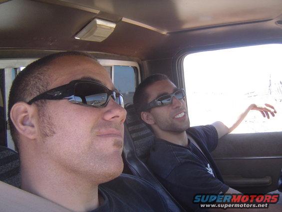 Interior of a truck cab with two men wearing sunglasses