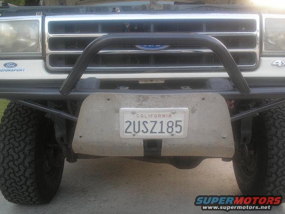 Front view of a white Ford truck with a chrome grille, brush guard, and aftermarket bumper with a California license plate