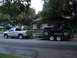1994 Jeep YJ - A Jeep Wrangler is transported on a trailer behind a pickup truck on a residential street.