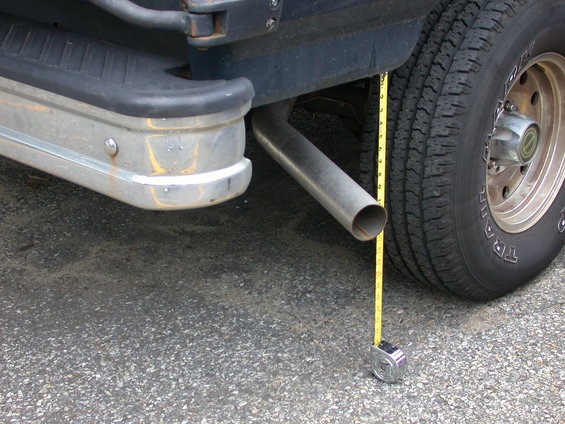Exhaust pipe measured with tape measure next to rear bumper and tire